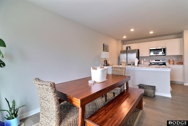 dining space with baseboards, wood finished floors, and recessed lighting