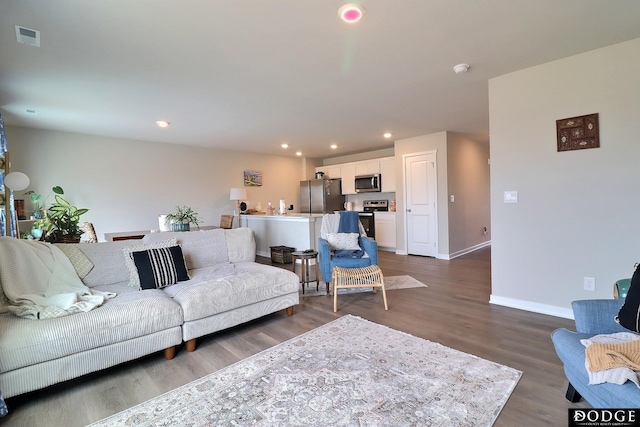 living room with recessed lighting, visible vents, baseboards, and wood finished floors