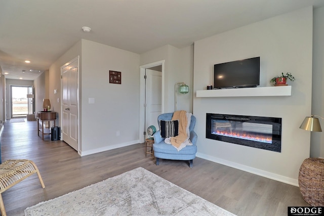 sitting room featuring wood finished floors, recessed lighting, a glass covered fireplace, and baseboards