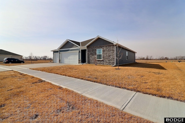 single story home with a garage, stone siding, concrete driveway, and a front yard