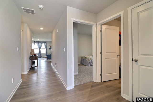 corridor with recessed lighting, visible vents, baseboards, and wood finished floors