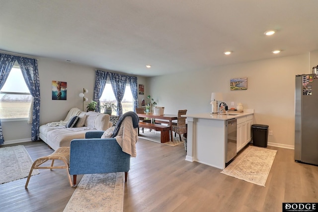 living room featuring light wood-type flooring, baseboards, and recessed lighting