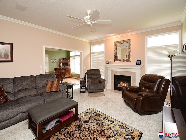 living area with carpet floors, a fireplace, ornamental molding, and a ceiling fan