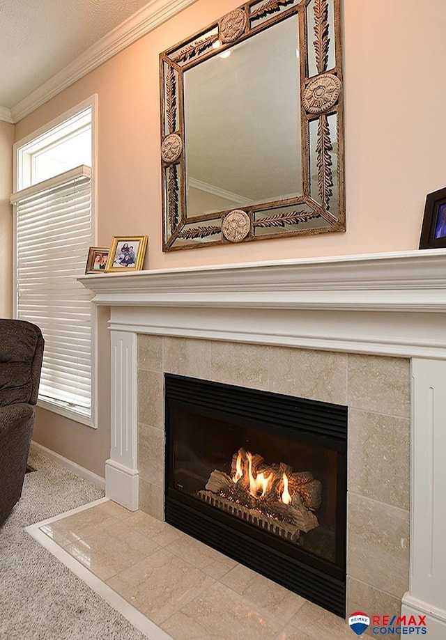 details with carpet floors, crown molding, baseboards, and a tiled fireplace