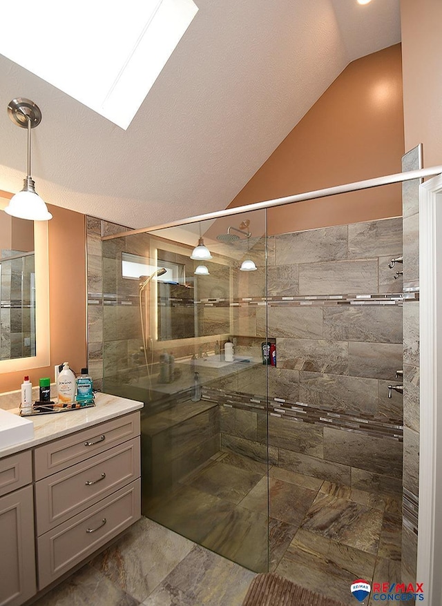 full bath with vaulted ceiling with skylight, a shower stall, vanity, and a textured ceiling