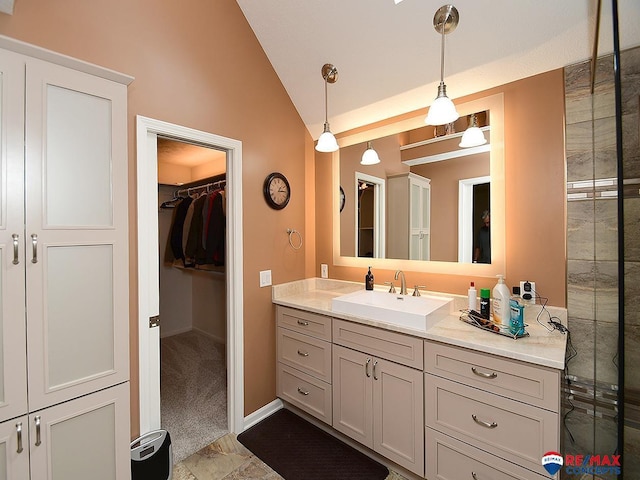 bathroom featuring vaulted ceiling, vanity, baseboards, and a spacious closet