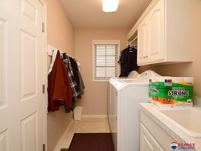 laundry room with cabinet space, light tile patterned floors, baseboards, washer and clothes dryer, and a sink