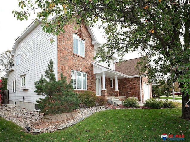 view of side of home with a yard, brick siding, and an attached garage