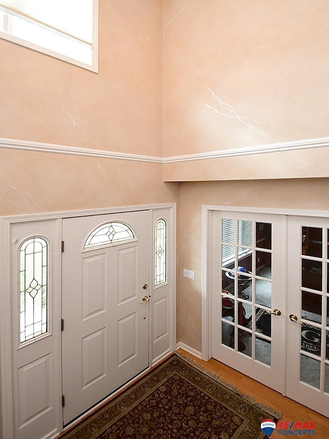 foyer entrance with french doors, a healthy amount of sunlight, and wood finished floors