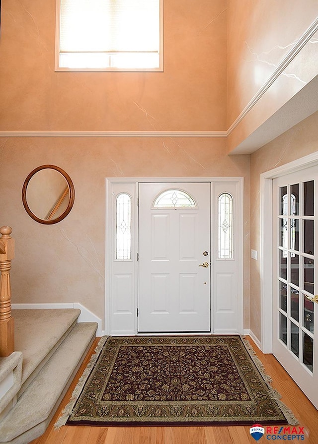 entrance foyer featuring stairs, a high ceiling, and wood finished floors