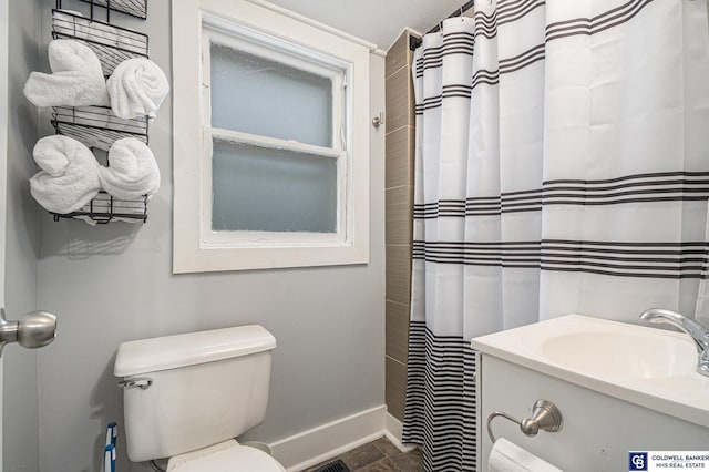 bathroom featuring toilet, stone finish flooring, a sink, a shower with curtain, and baseboards