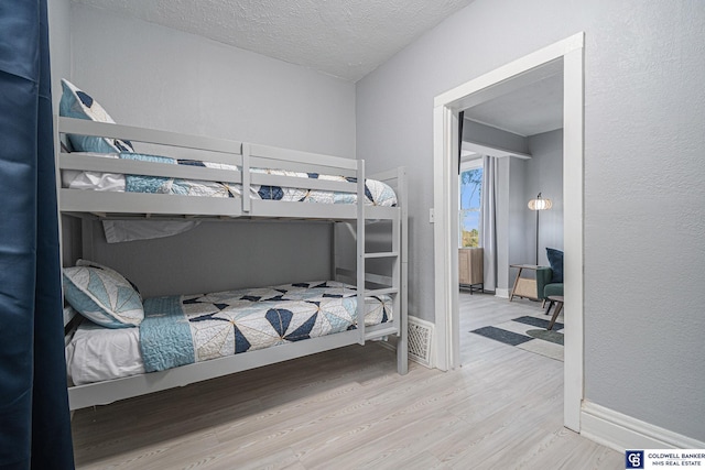 bedroom featuring a textured ceiling, baseboards, and wood finished floors