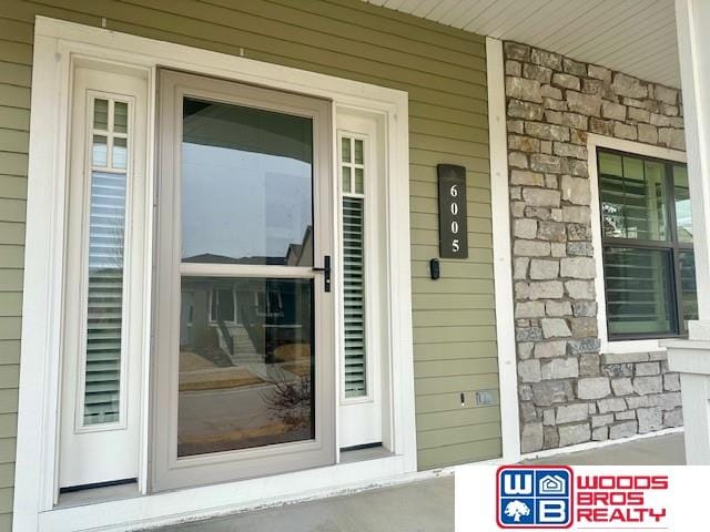 property entrance with stone siding and covered porch