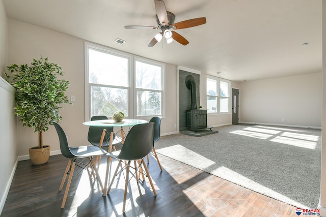 dining area with a wood stove, visible vents, baseboards, and wood finished floors