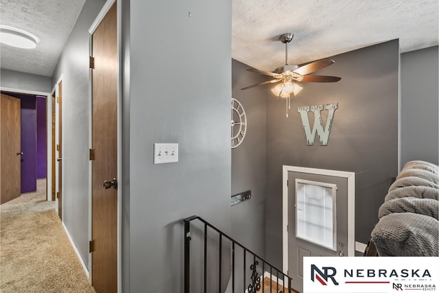 stairs featuring a ceiling fan, carpet flooring, and a textured ceiling