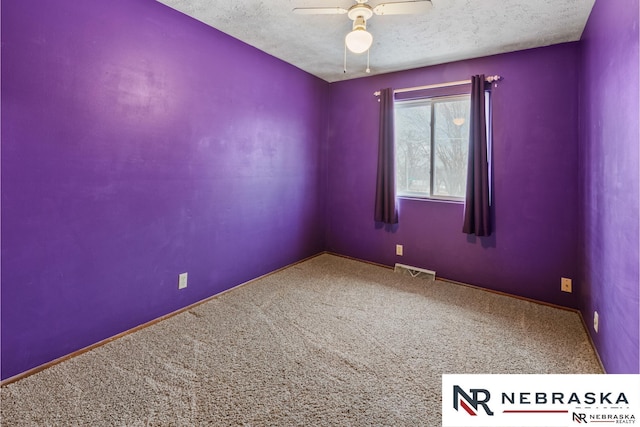 spare room with carpet, visible vents, ceiling fan, and a textured ceiling