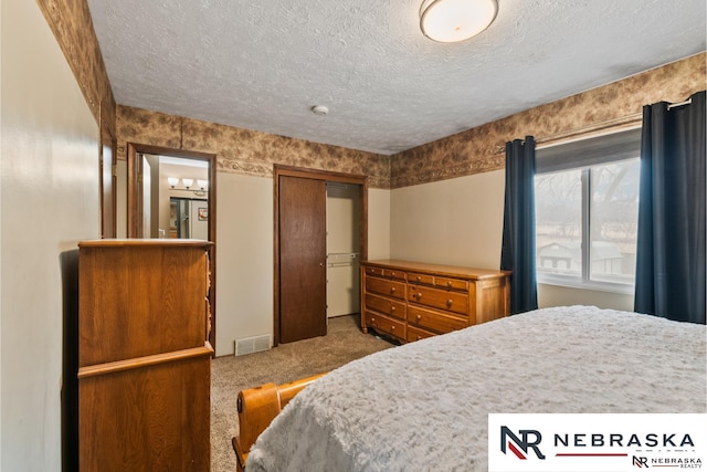 carpeted bedroom featuring a textured ceiling, a closet, and visible vents