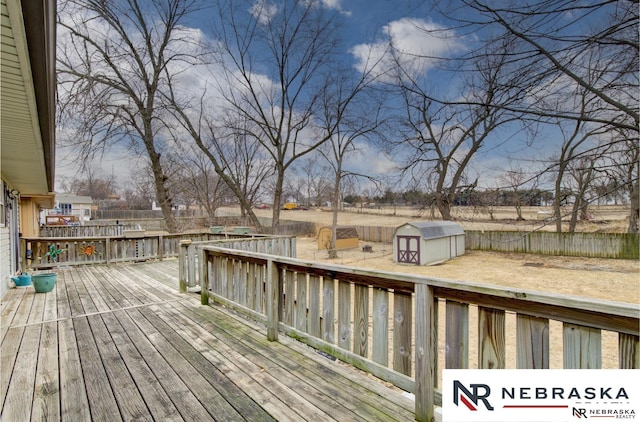 wooden terrace featuring a fenced backyard, an outdoor structure, and a storage shed