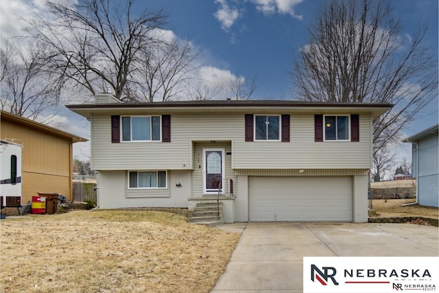 raised ranch with a garage, concrete driveway, and a chimney