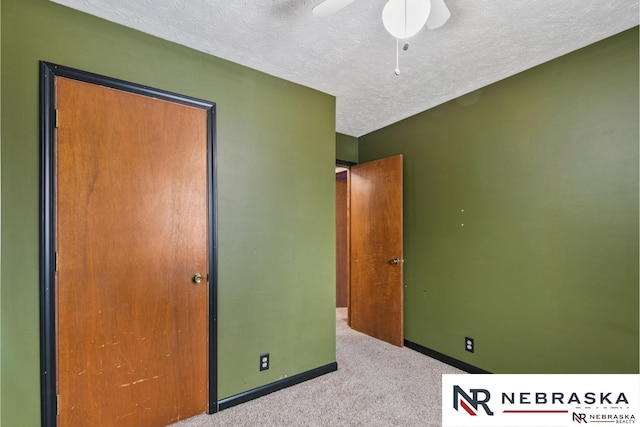 unfurnished bedroom with carpet, ceiling fan, a textured ceiling, and baseboards