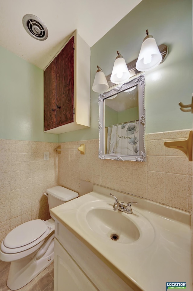 full bathroom featuring toilet, vanity, visible vents, tile walls, and tile patterned floors