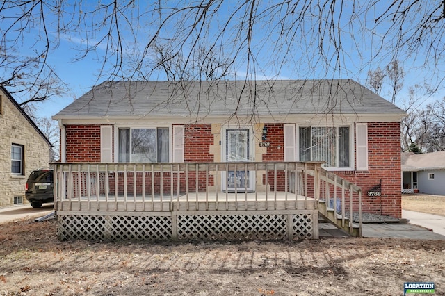 bungalow-style house featuring a deck and brick siding