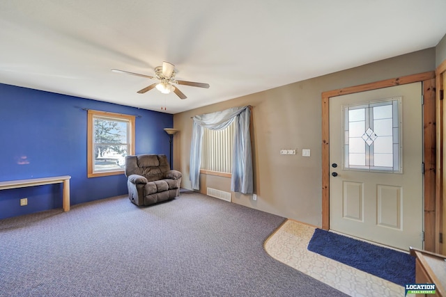 carpeted entrance foyer with visible vents and a ceiling fan