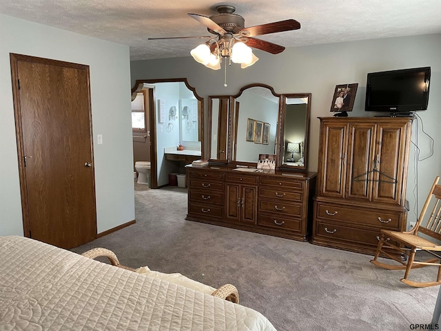 bedroom with a textured ceiling, carpet, connected bathroom, and baseboards