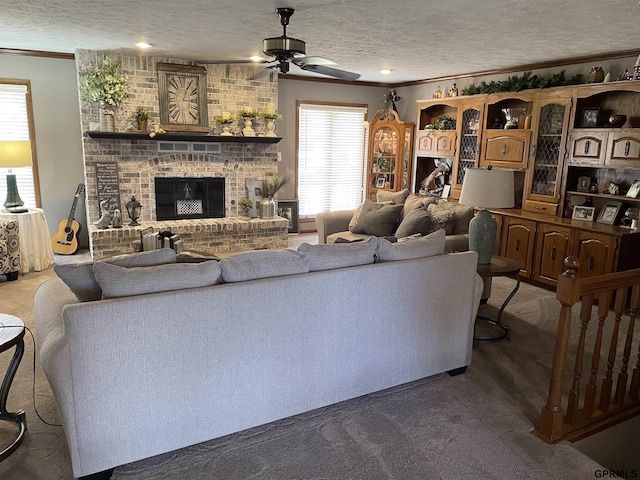 carpeted living area with crown molding, a fireplace, a textured ceiling, and ceiling fan