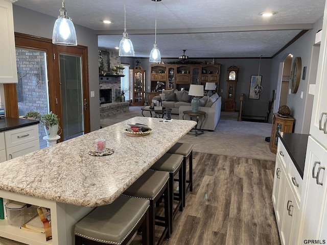 kitchen with arched walkways, a breakfast bar, a center island, a fireplace, and a textured ceiling