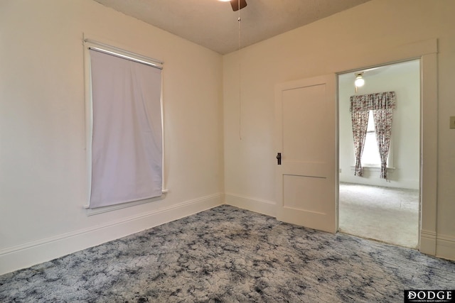 carpeted empty room with baseboards and a ceiling fan