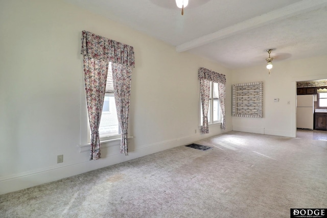 carpeted spare room featuring beam ceiling, a ceiling fan, and a healthy amount of sunlight