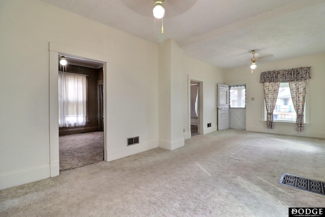 empty room featuring carpet floors, visible vents, ceiling fan, and baseboards