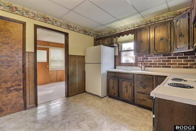 kitchen featuring a paneled ceiling, light countertops, freestanding refrigerator, wainscoting, and dark brown cabinetry