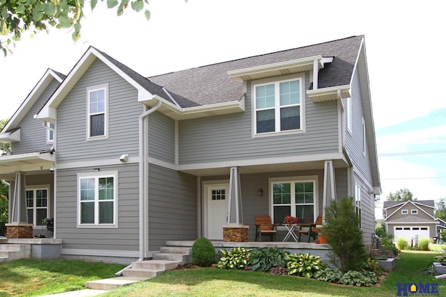 craftsman inspired home with a porch, a shingled roof, and a front lawn