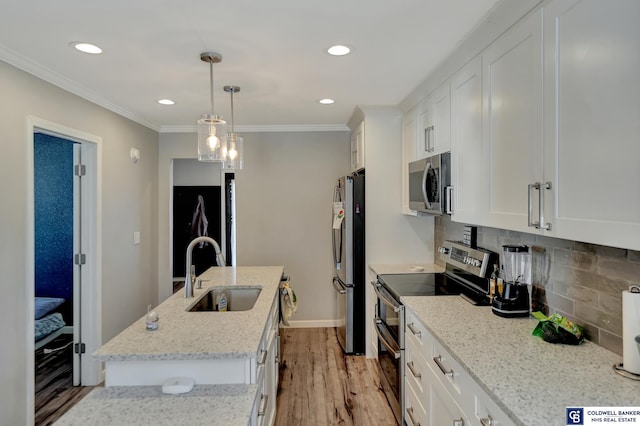 kitchen featuring a sink, ornamental molding, appliances with stainless steel finishes, decorative backsplash, and a center island with sink