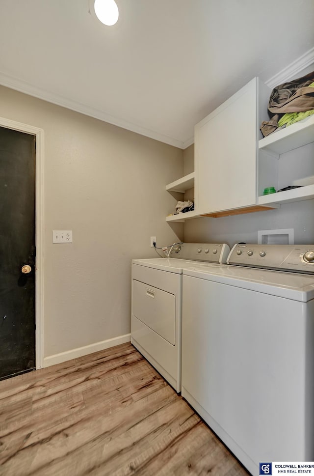 clothes washing area with laundry area, baseboards, ornamental molding, light wood-style floors, and washing machine and dryer