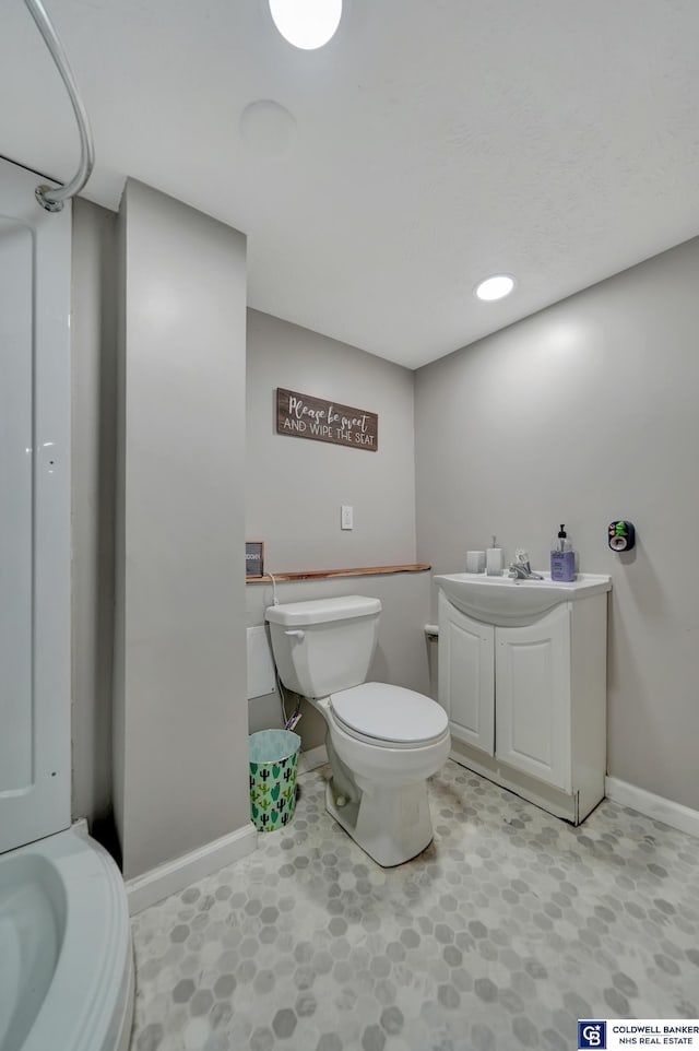 bathroom featuring toilet, baseboards, and a sink