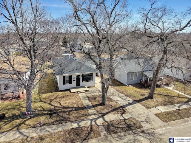 view of front of property featuring a shingled roof, a front yard, and driveway