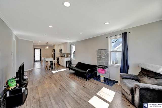 living room featuring light wood-style flooring, ornamental molding, and a wealth of natural light