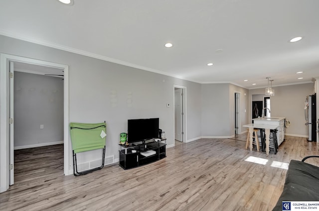 living area featuring light wood-style floors, recessed lighting, ornamental molding, and baseboards