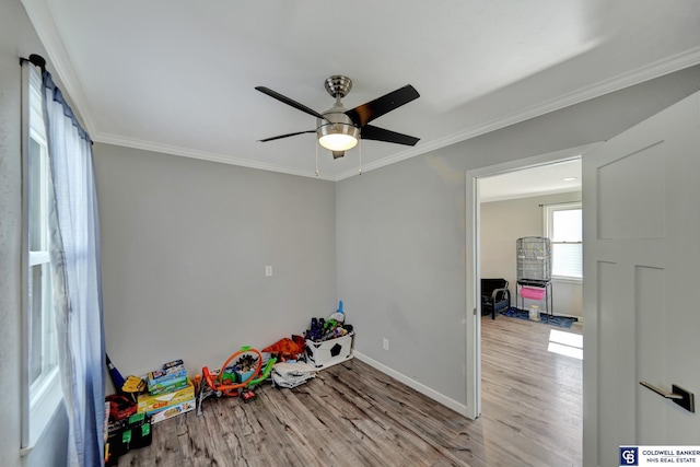 playroom with a ceiling fan, baseboards, ornamental molding, and wood finished floors