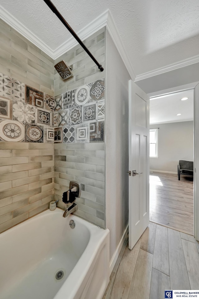 full bathroom featuring baseboards, wood finished floors, a bathtub, crown molding, and a textured ceiling