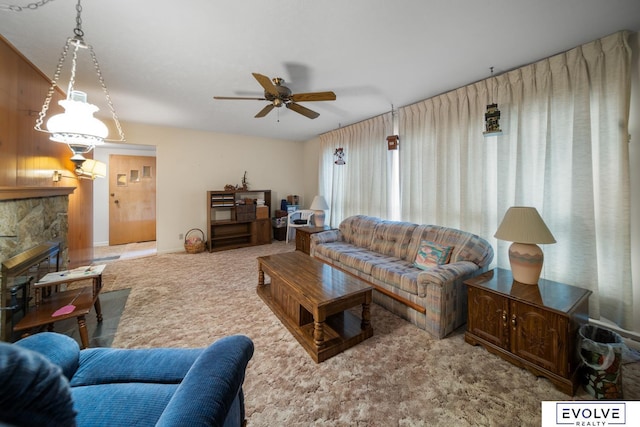 living area with a fireplace, ceiling fan, and carpet floors