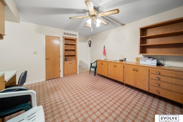 office with built in features, visible vents, baseboards, and ceiling fan