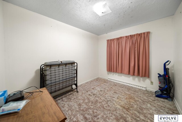 misc room with a textured ceiling, a baseboard heating unit, baseboards, and carpet floors