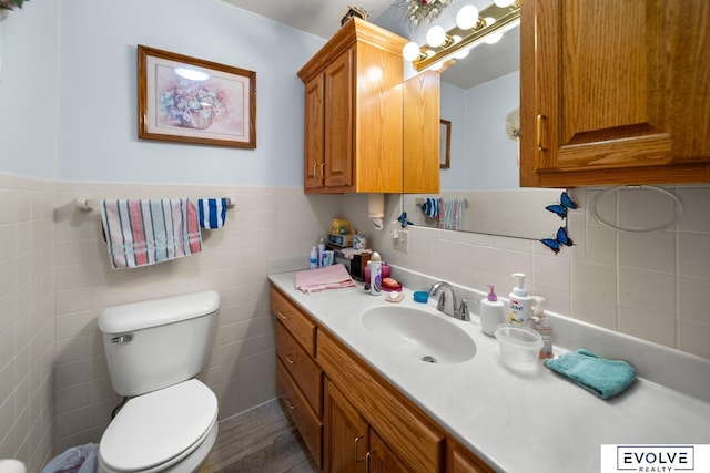 bathroom with a wainscoted wall, toilet, tile walls, and vanity