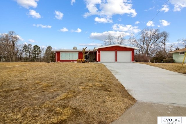 view of front of house featuring driveway, an attached garage, a chimney, and a front yard