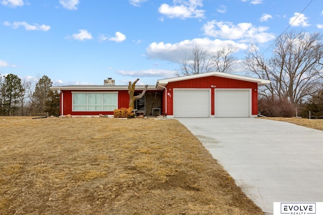 ranch-style house featuring concrete driveway, a chimney, a garage, and a front lawn