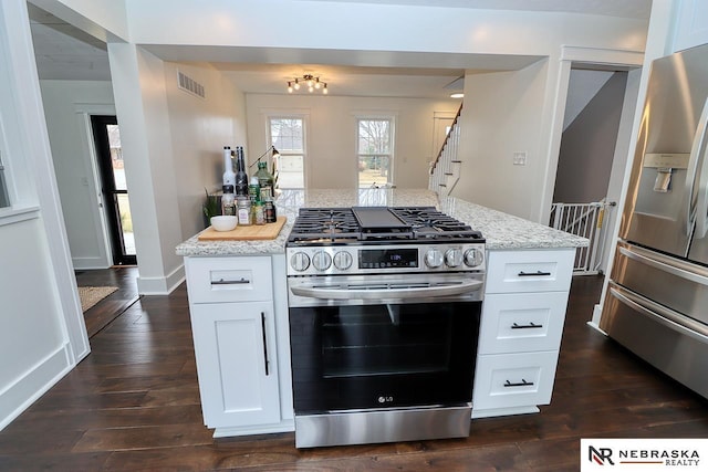 kitchen featuring stainless steel appliances, light stone counters, dark wood-type flooring, and visible vents